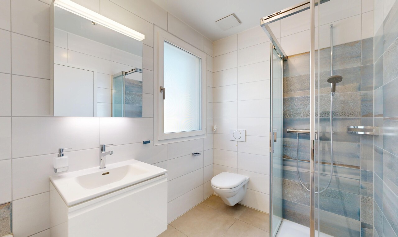 salle de bains avec tile wall, mur en carrelage, lavabo (ou coiffeuse selon le contexte), miroir, et douche