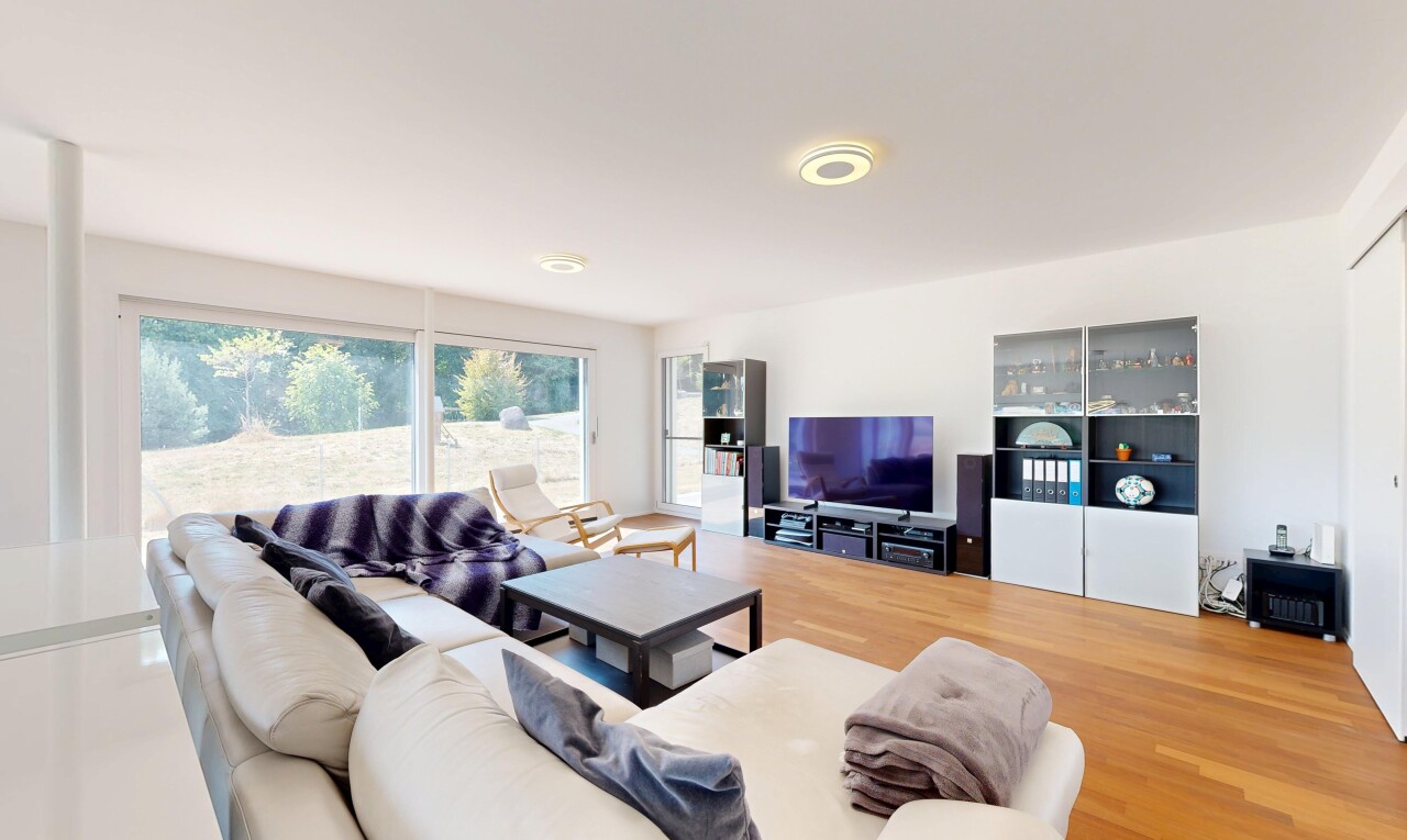 salon avec télévision, drywall, cloison sèche, wood finish floor, et sol en finition bois