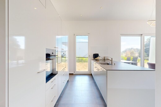 cuisine avec kitchen peninsula, péninsule de cuisine, lumière naturelle, dark floor, et flat panel cabinets