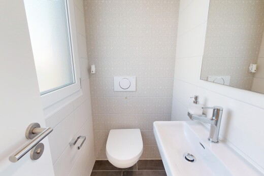 salle de bains avec mur en carrelage, tile wall, toilette, évier, et miroir