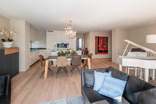 wohn- / esszimmer mit bemerkenswerter kronleuchter, holzfußboden, wood finish floor, inside property, und gipskartonwand