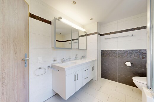 salle de bains avec tile wall, mur en carrelage, double vasque, light floor, et miroir