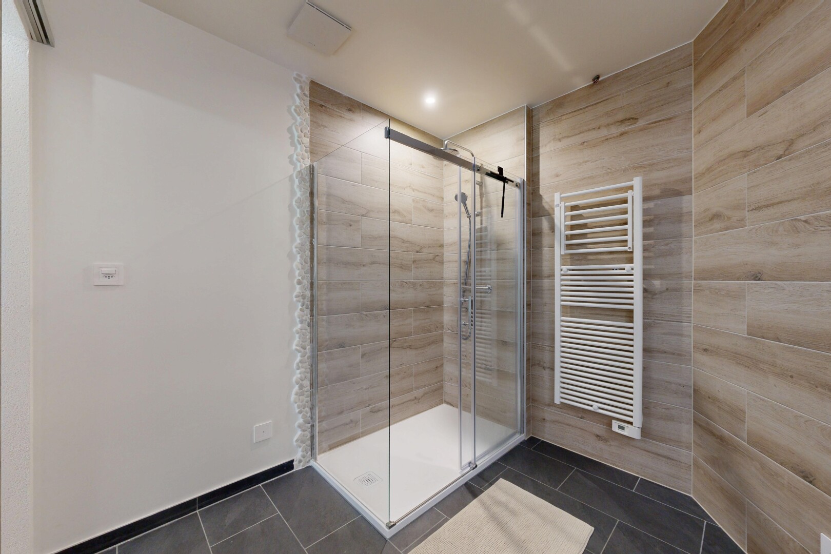 salle de bains avec dark floor, douche, chauffe-serviettes, radiateur, et salle de bain complète