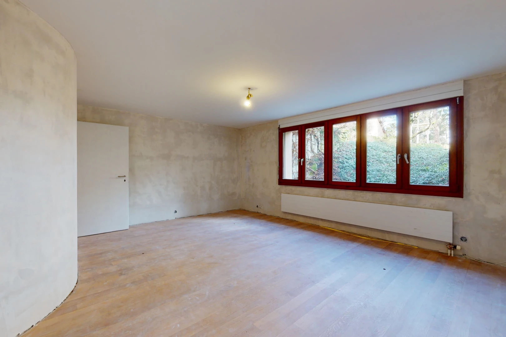 chambre vide avec lumière naturelle, parquet, et radiateur