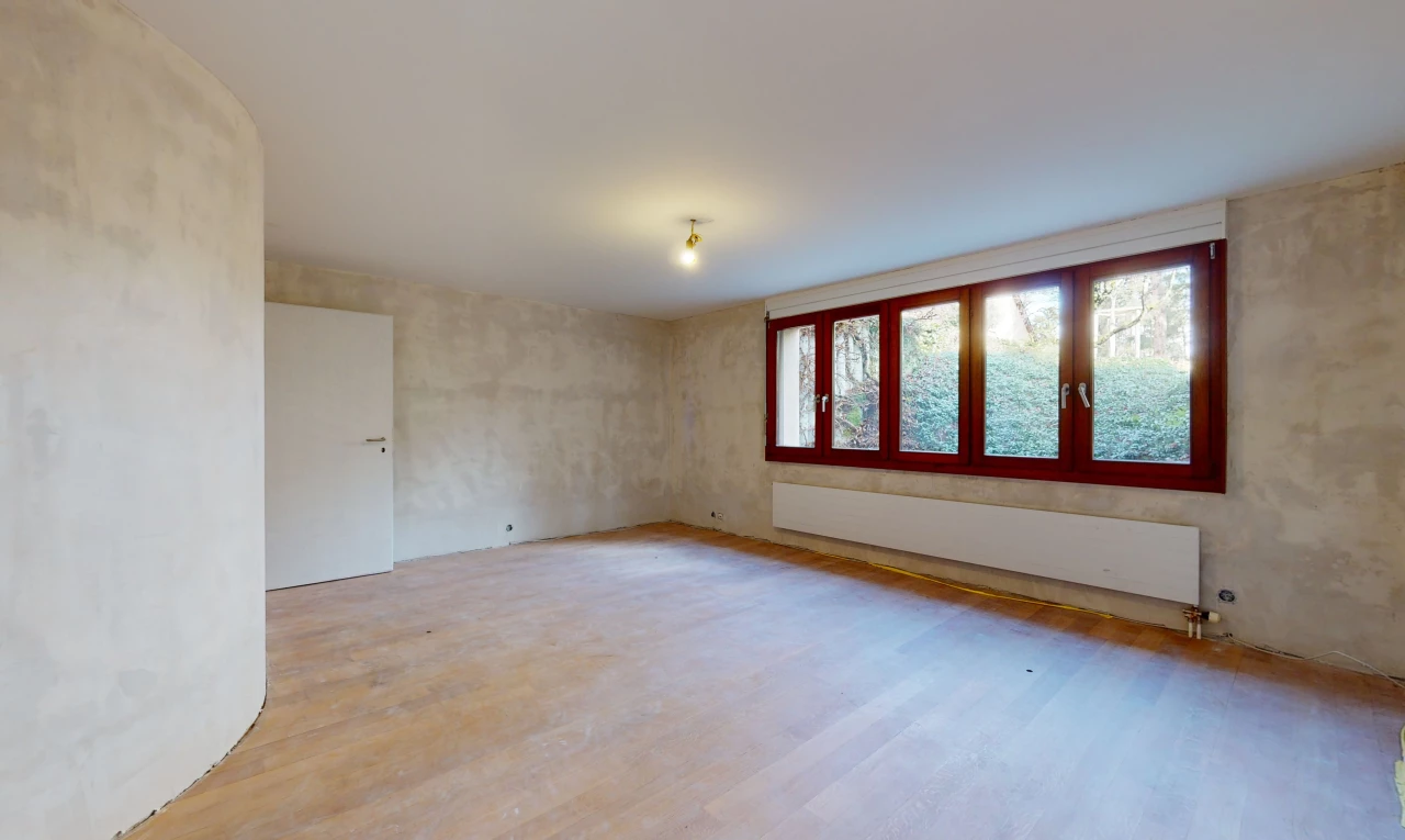chambre vide avec lumière naturelle, parquet, et radiateur