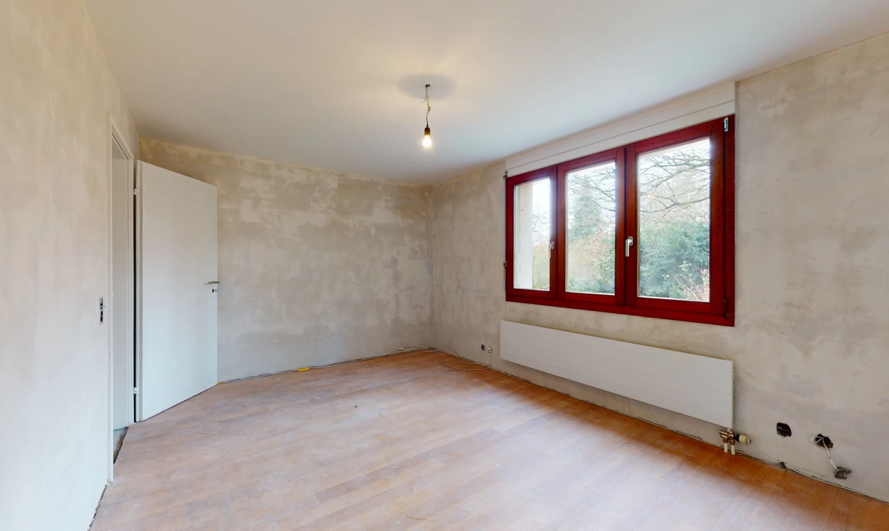 chambre vide avec lumière naturelle, parquet, et radiateur
