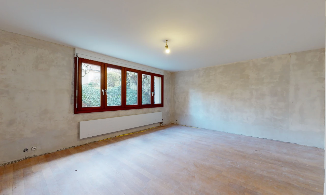 chambre vide avec lumière naturelle, parquet, et radiateur