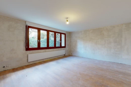 chambre vide avec lumière naturelle, parquet, et radiateur