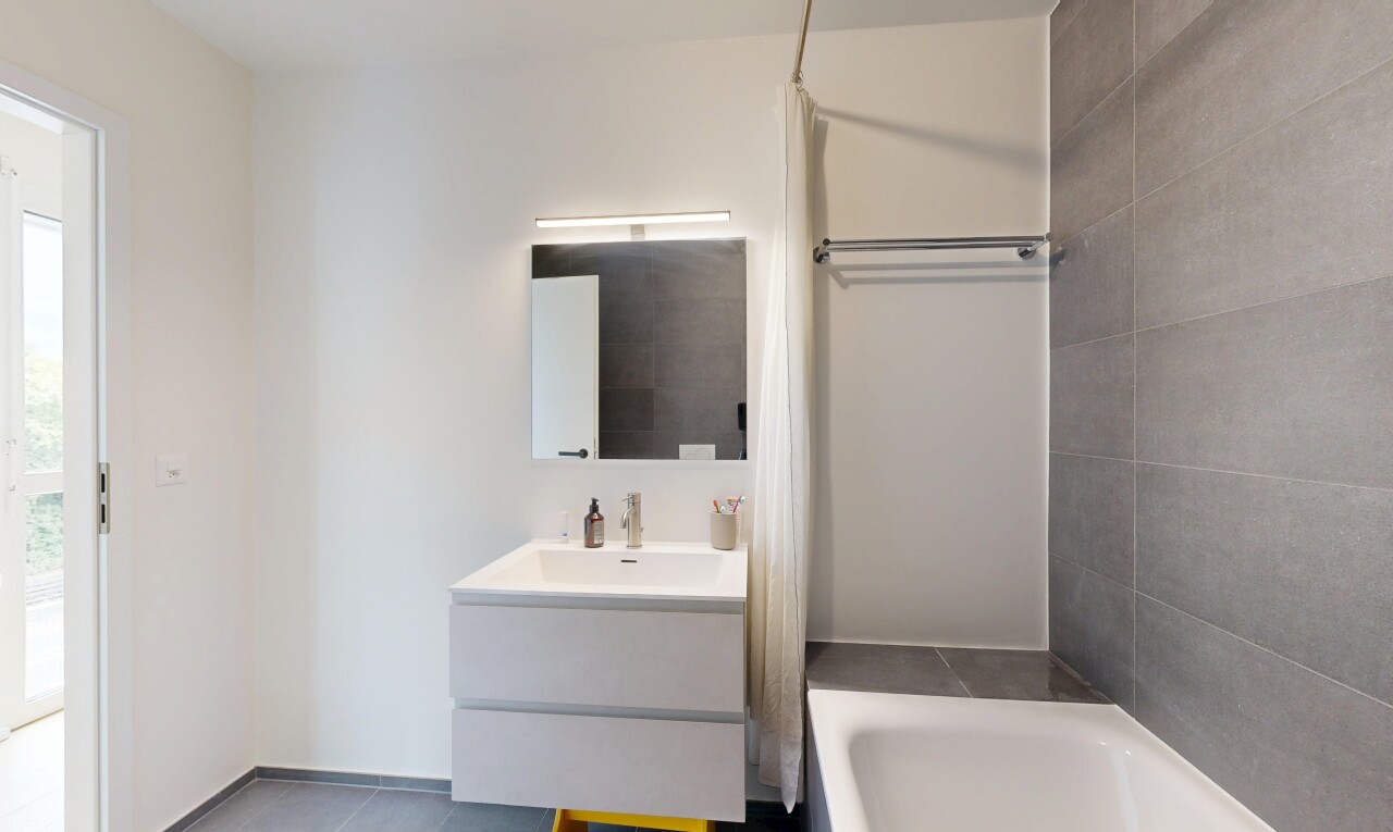 salle de bains avec salle de bain complète, lavabo (ou coiffeuse selon le contexte), miroir, drywall, et cloison sèche