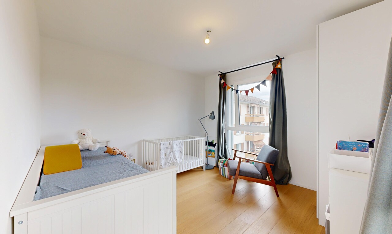 chambre avec drywall, cloison sèche, wood finish floor, sol en finition bois, et lumière naturelle