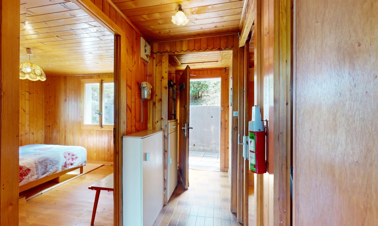 room / bedroom featuring multiple windows, light wood-style floors, wood walls, and wooden ceiling