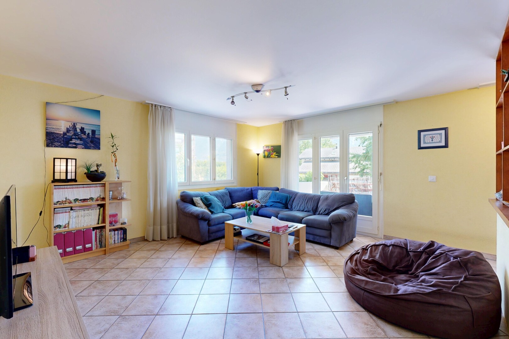 salon avec éclairage sur rail, cloison sèche, drywall, sol en carrelage, et tile floor