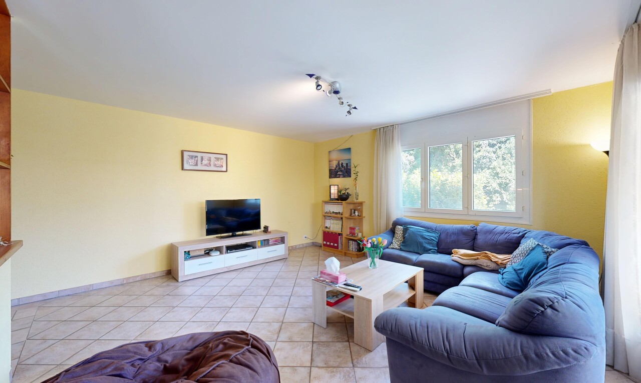 salon avec cloison sèche, drywall, télévision, sol en carrelage, et tile floor