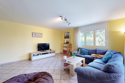 salon avec cloison sèche, drywall, télévision, sol en carrelage, et tile floor
