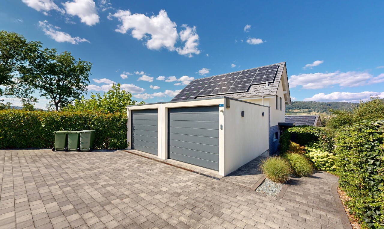 view of property with solar panels, driveway, and stucco siding