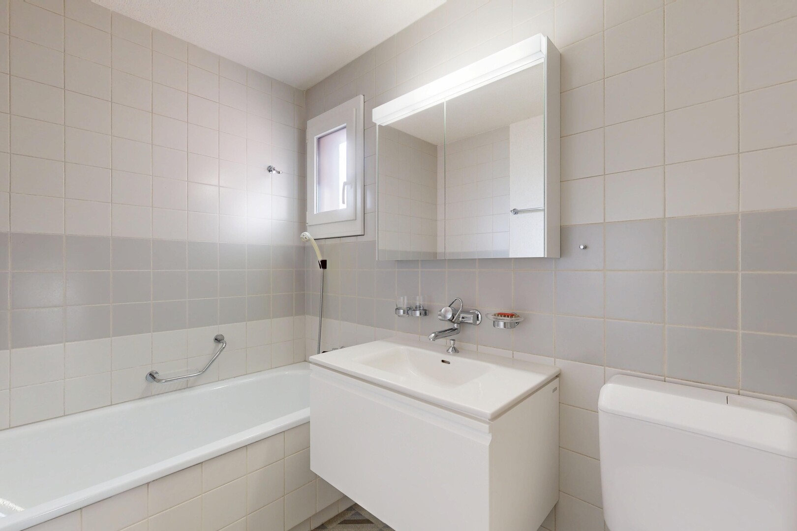 salle de bains avec tile wall, mur en carrelage, miroir, lavabo (ou coiffeuse selon le contexte), et salle de bain complète