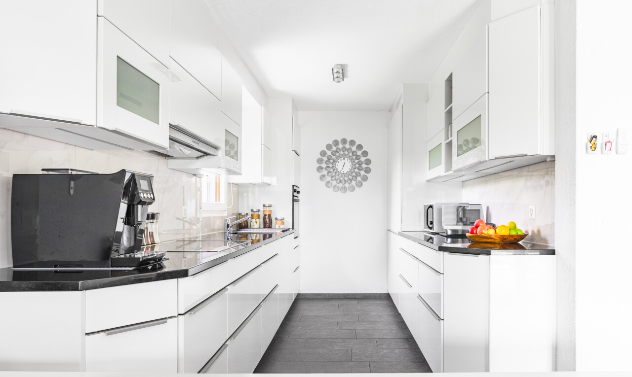 kitchen featuring tasteful backsplash, modern cabinets, white cabinetry, glass insert cabinets, and stainless steel microwave