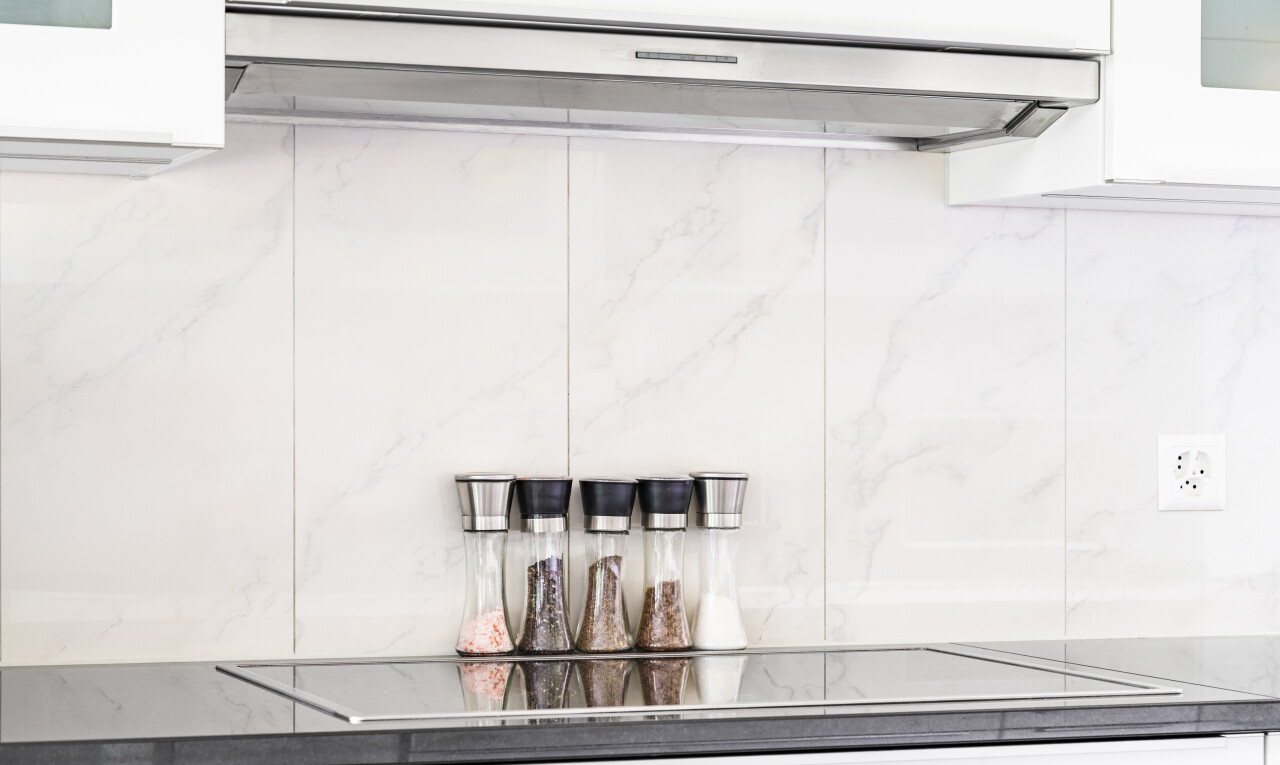 kitchen view of ventilation hood, white cabinetry, black electric stovetop, and light stone counters