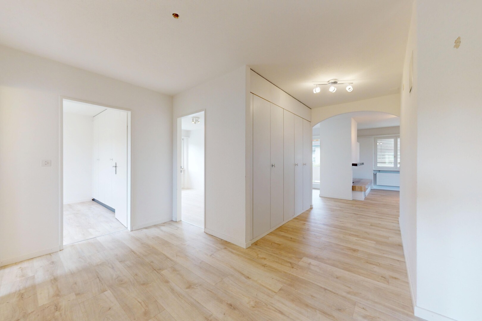 pièce vide avec passages en arc, sol en finition bois, wood finish floor, inside property, et cloison sèche