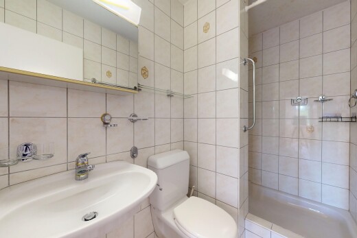 bathroom with tiled shower, a sink, toilet, and tile walls