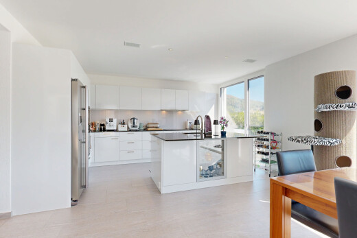 kitchen with modern cabinets, white cabinets, dark countertops, freestanding refrigerator, and a kitchen island with sink