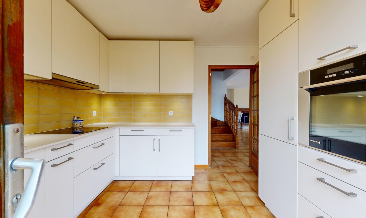 cuisine avec armoires blanches, four, plans de travail, backsplash, et dosseret