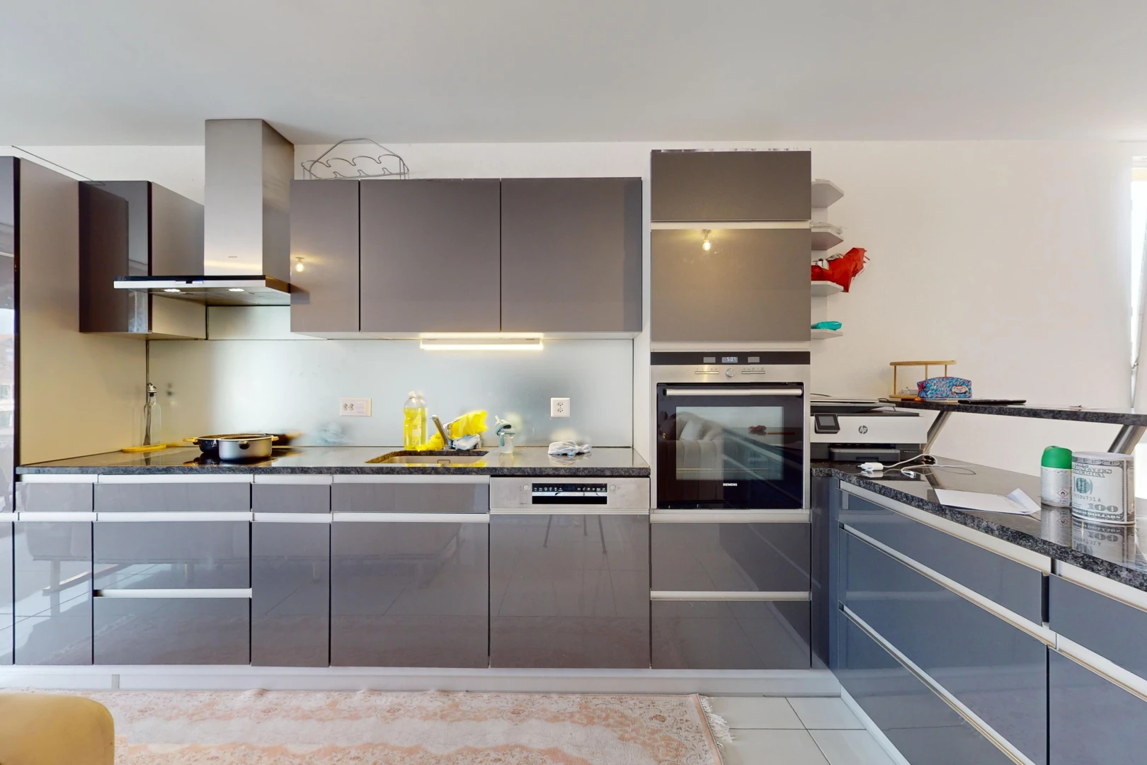 cuisine avec hotte, meubles à panneaux plats, plan de travail en pierre, et four