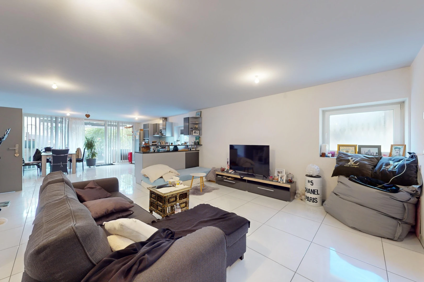 salon avec carrelage, télévision, et lumière naturelle