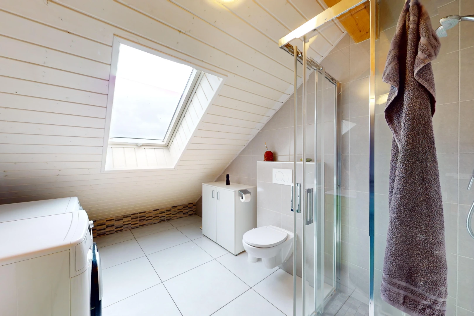 salle de bains avec toilettes, plafond voûté, machine à laver / sèche-linge séparés, lucarne, et douche