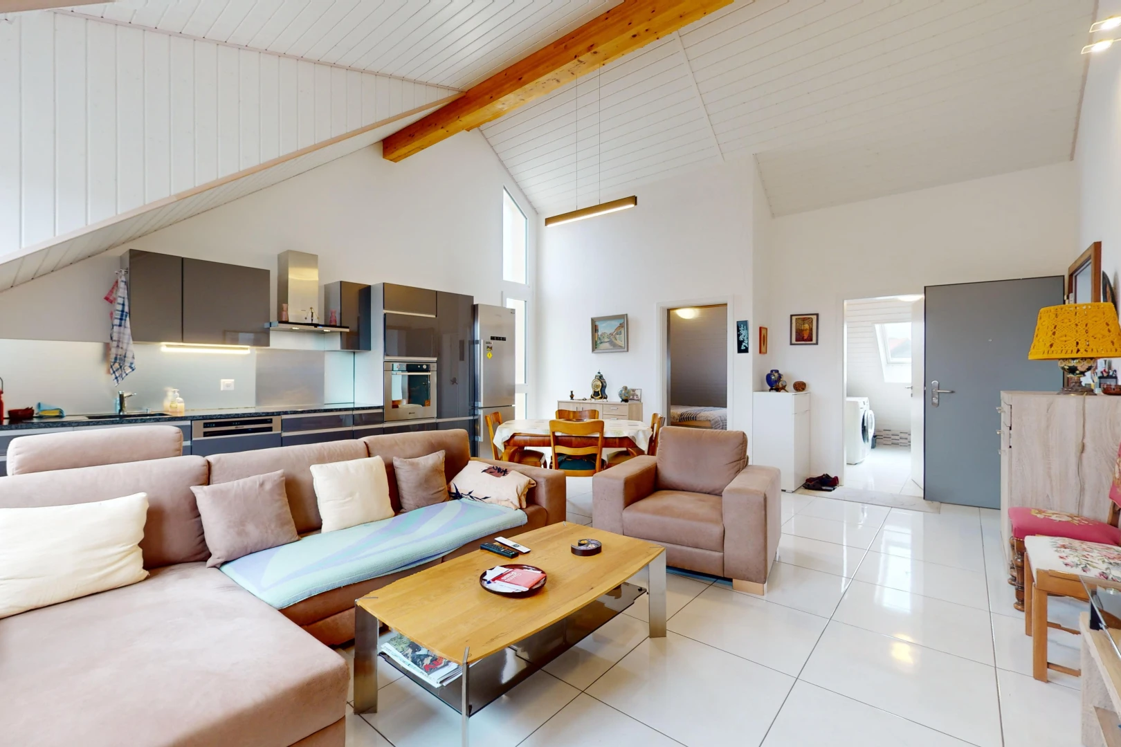 salon avec haut plafond, poutres apparentes, carrelage, lumière naturelle, et plafond voûté