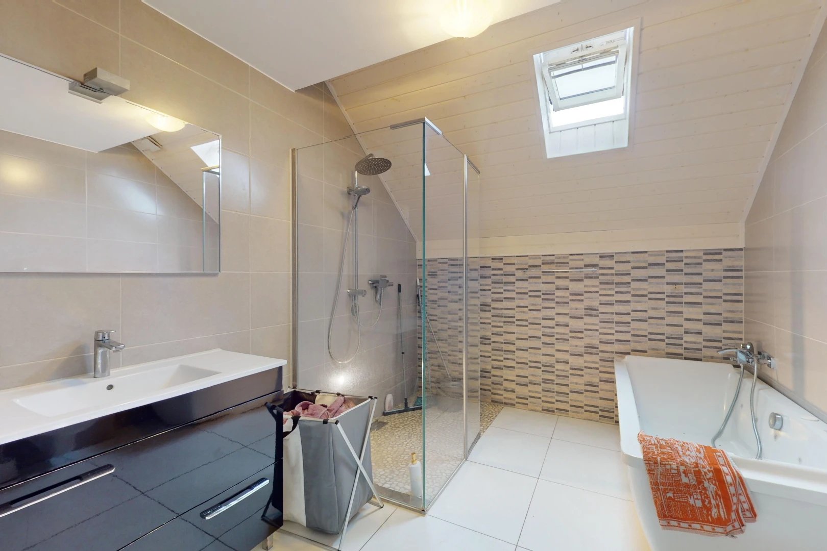 salle de bains avec meuble-lavabo, baignoire, miroir, mur carrelé, et douche