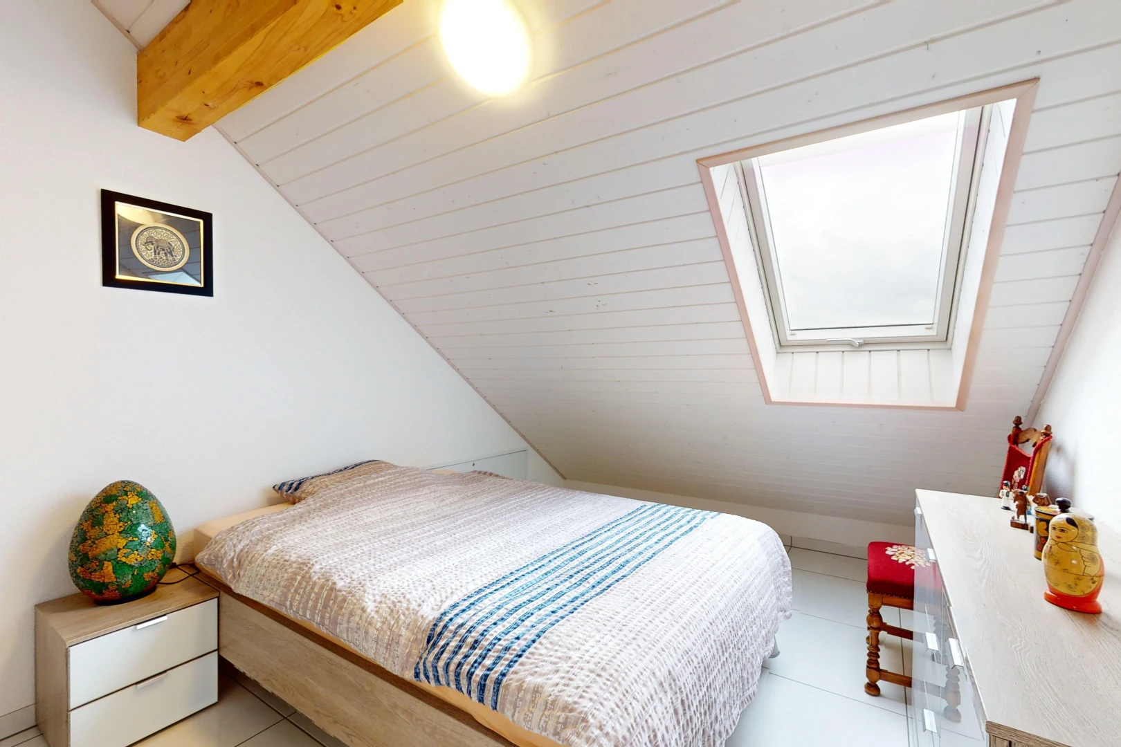 chambre avec poutres apparentes, carrelage, lumière naturelle, plafond voûté, et lucarne