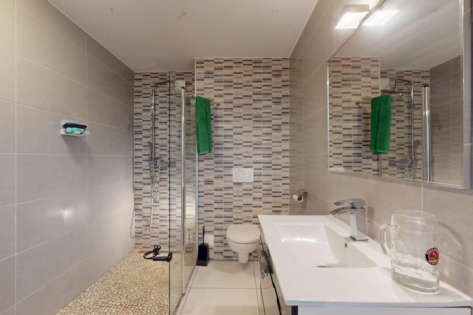 salle de bains avec meuble-lavabo, toilettes, mur carrelé, et douche