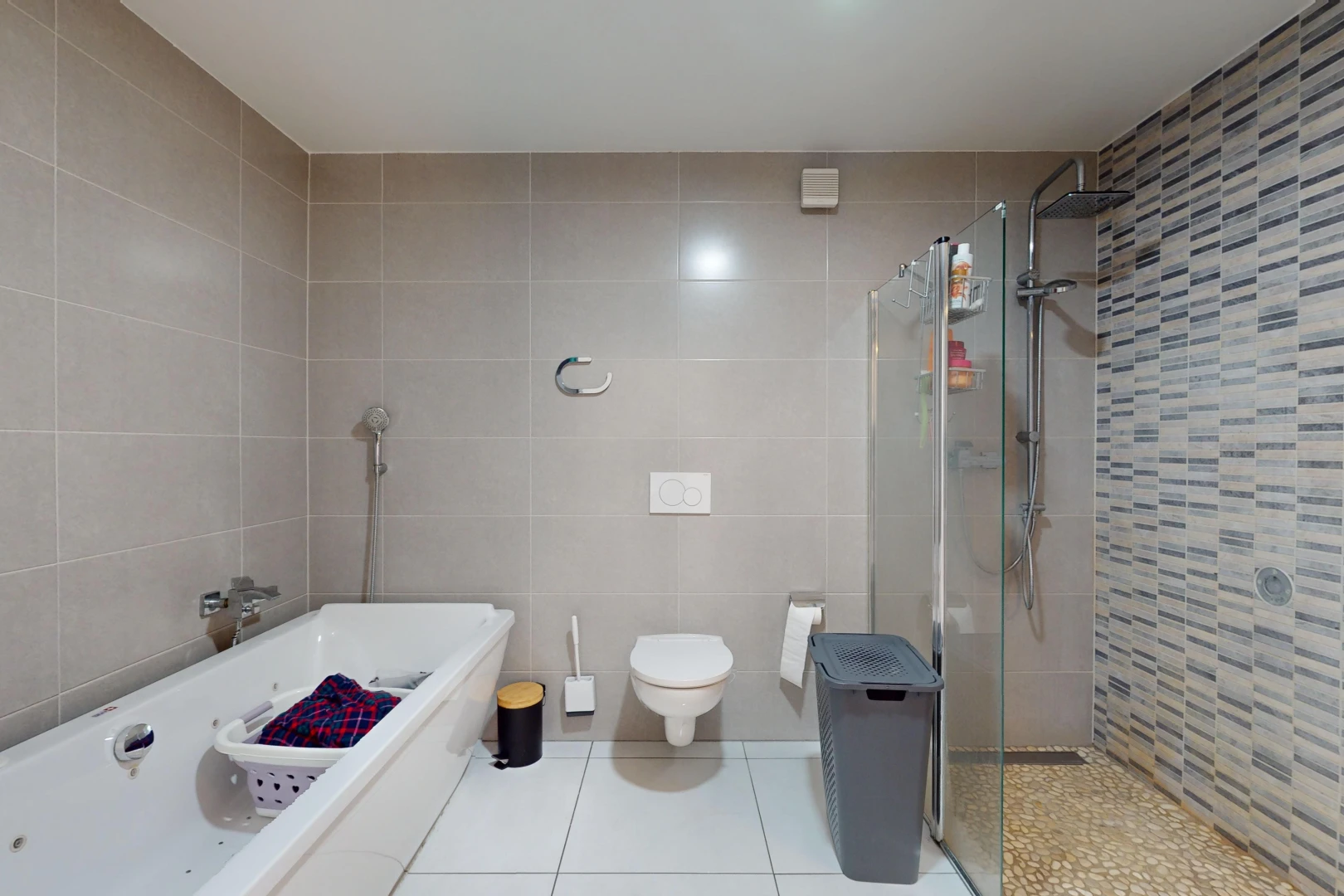salle de bains avec baignoire, douche, mur carrelé, et toilettes