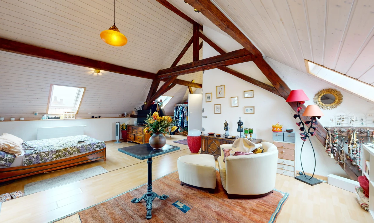 chambre avec plancher de bois, poutres apparentes, plafond voûté, et lucarne