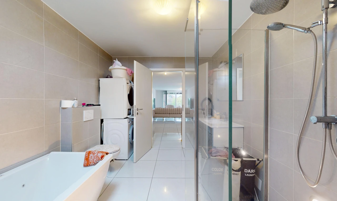 salle de bains avec machine à laver / sèche-linge superposés, baignoire, carrelage, mur carrelé, et douche