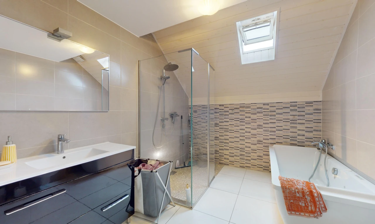 salle de bains avec meuble-lavabo, baignoire, miroir, mur carrelé, et douche