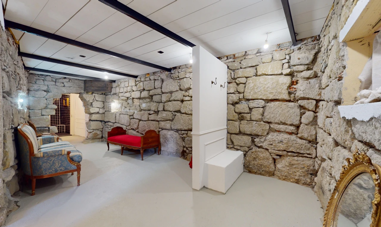 salon avec mur en pierre, sol en béton, poutres apparentes, et plafond de bois