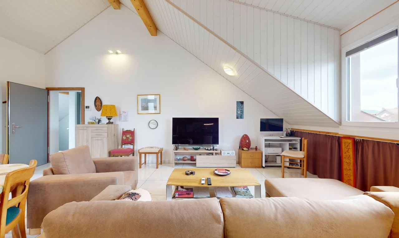 salon avec télévision, haut plafond, plafond voûté, et poutres apparentes