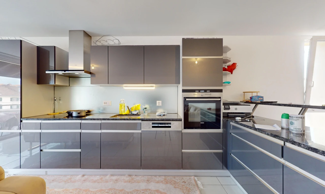 cuisine avec hotte, meubles à panneaux plats, plan de travail en pierre, et four