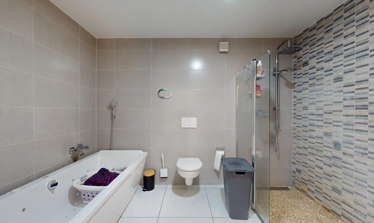 salle de bains avec baignoire, douche, mur carrelé, et toilettes