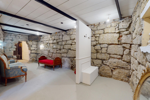 salon avec mur en pierre, sol en béton, poutres apparentes, et plafond de bois