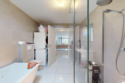 salle de bains avec machine à laver / sèche-linge superposés, baignoire, carrelage, mur carrelé, et douche