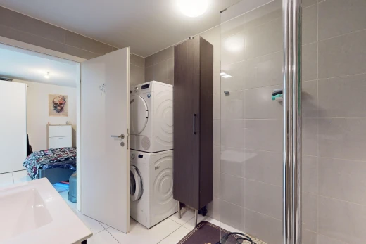 bathroom featuring stacked washing maching and dryer, a shower with door, and tile patterned flooring