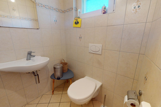 salle de bains avec mur carrelé, toilettes, lumière naturelle, et carrelage