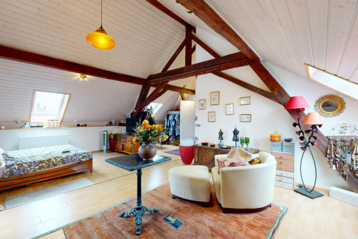 chambre avec plancher de bois, poutres apparentes, plafond voûté, et lucarne