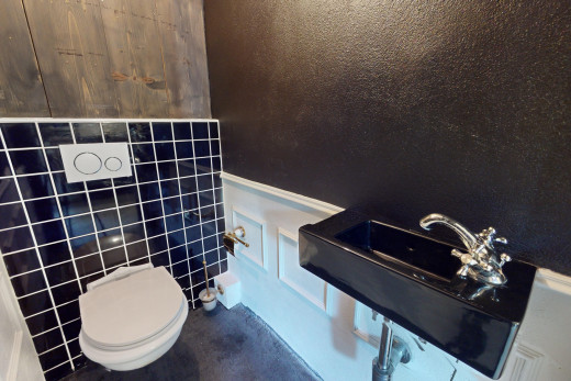 salle de bains avec toilettes et mur carrelé