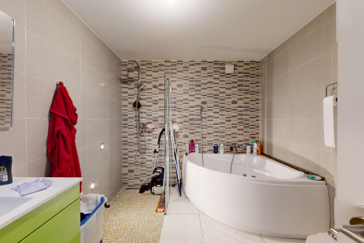 salle de bains avec mur carrelé, carrelage, baignoire, et meuble-lavabo