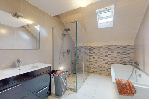 salle de bains avec meuble-lavabo, baignoire, miroir, mur carrelé, et douche