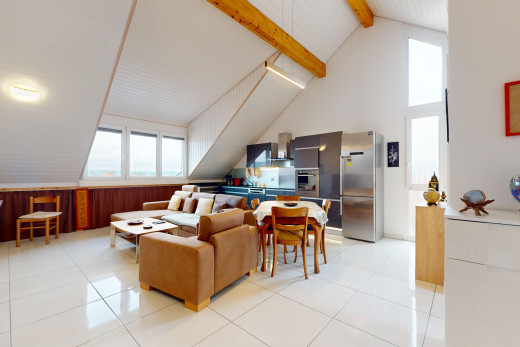 salon / salle à manger avec poutres apparentes, mur en bois, carrelage, lumière naturelle, et plafond voûté